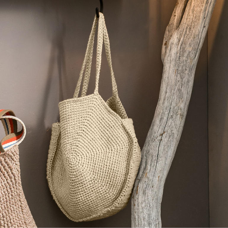 Häkelte Tasche mit 32 cm Durchmesser aus Contrato und Cotonia II an einer Wand.