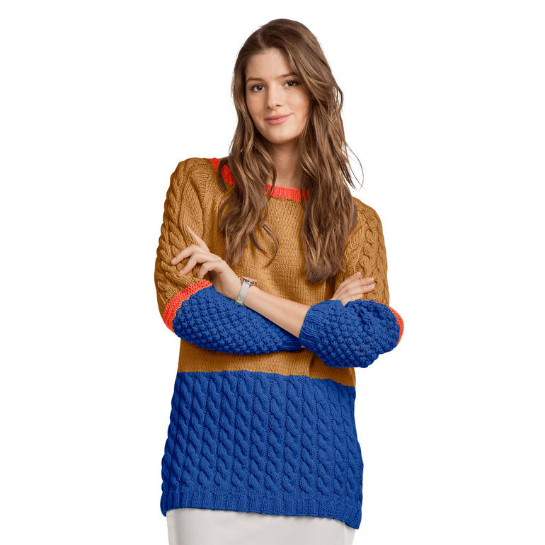 Dame in buntem Oversize-Pullover mit langen Ärmeln, lächelt in die Kamera.