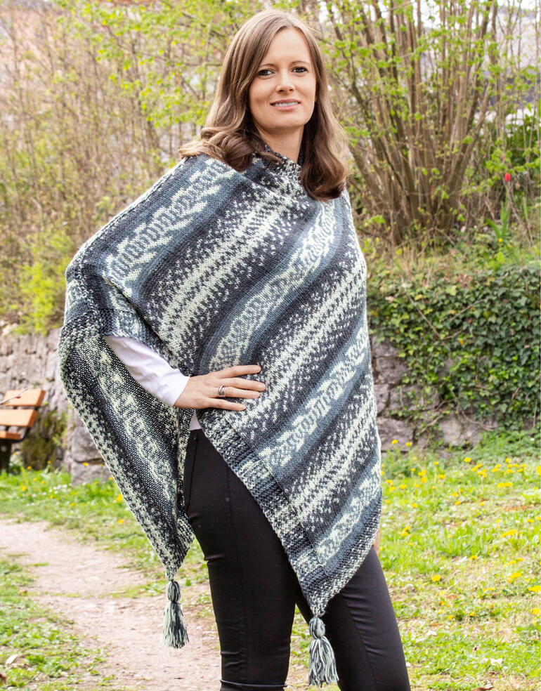 Poncho in Blau und Grau mit Muster, getragen von einer Frau im Freien.