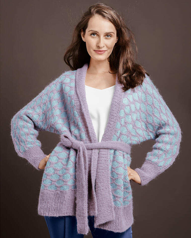 Dame in lila Jacke mit bunten Mustern, lächelnd in die Kamera.