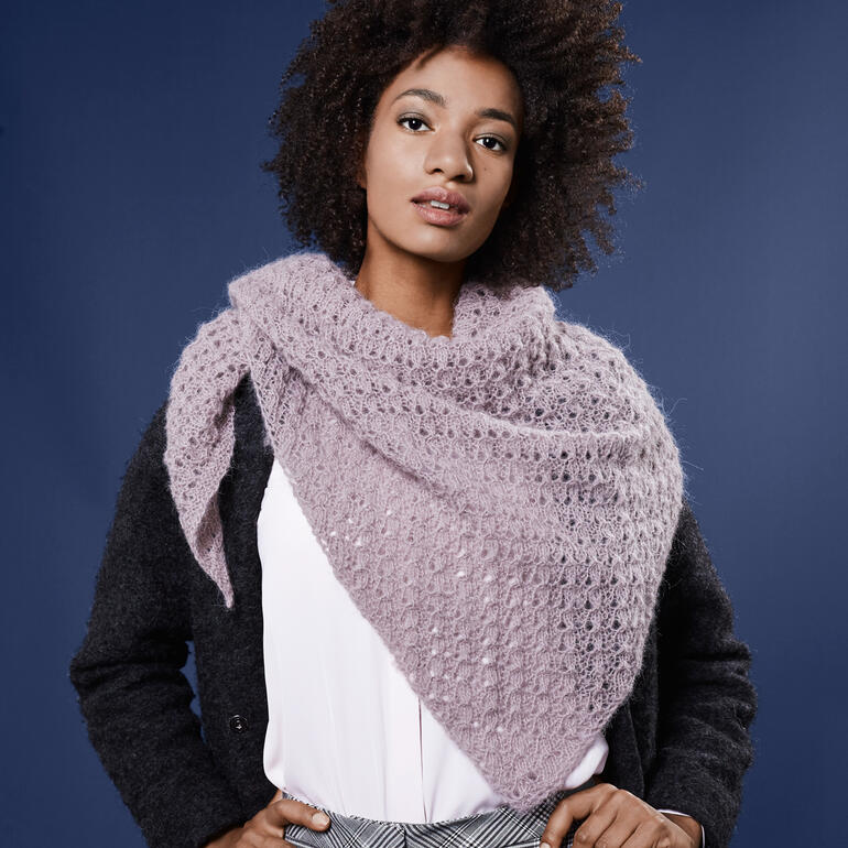 Dame trägt helllila Tuch, lächelnd vor blauem Hintergrund.