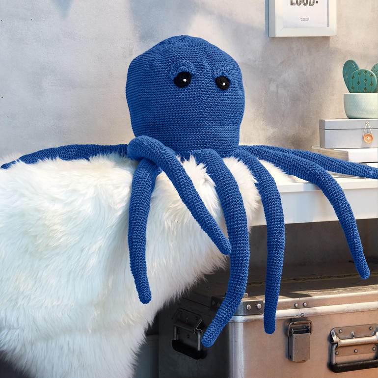 Häkelkrake aus Cotonara in Blau, dekorativ auf einem Tisch platziert.