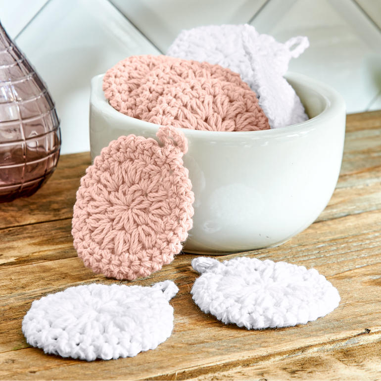 Häkelkosmetikpads in rosa und weiß in einer grauen Schüssel.