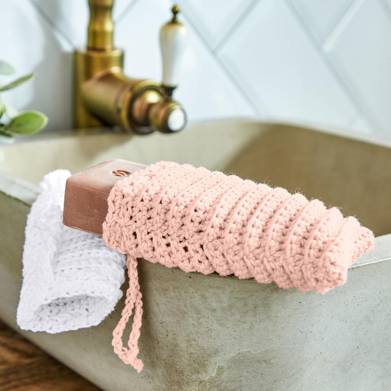 Häkel-Seifensäckchen mit Seife am Waschbecken.
