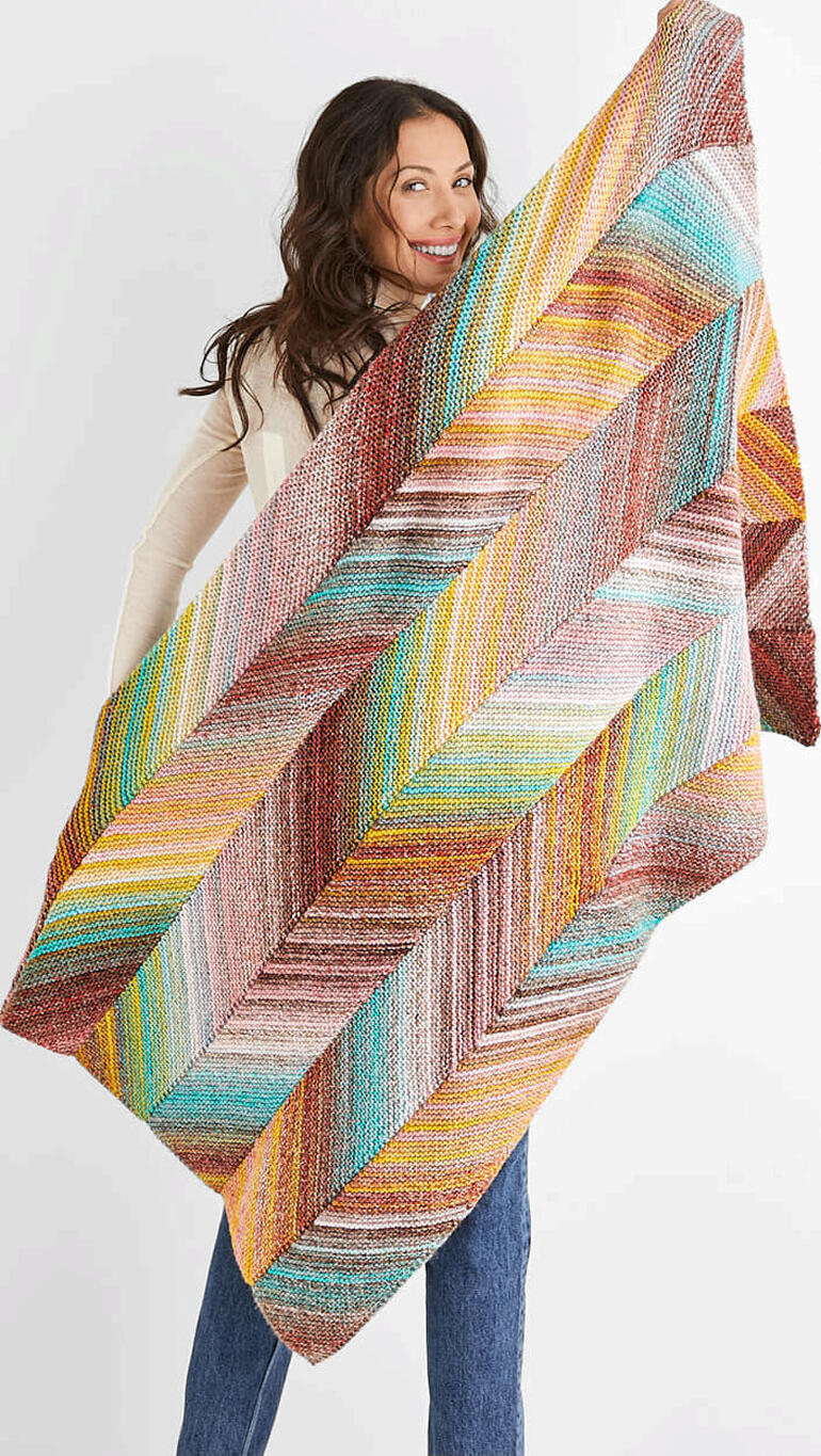 Frau hält eine farbenfrohe Decke mit gestreiftem Muster in den Händen.