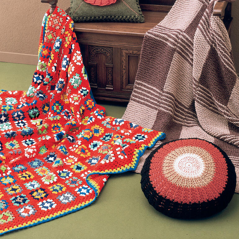 Bunte Patchworkdecke aus Poco, auf einem Sofa, mit zwei weiteren Decken.