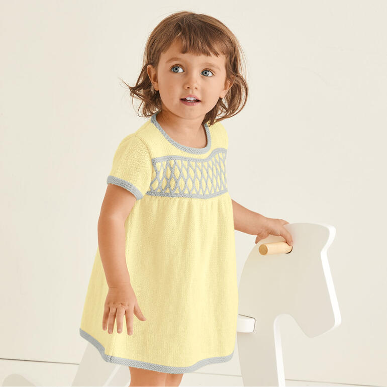 Gelbes Kinderkleidchen mit gehäkelten Details.