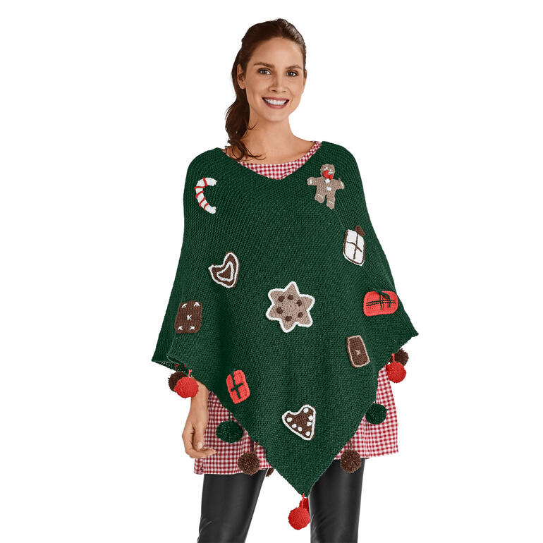 Dame trägt grünen Poncho mit bunten Weihnachtsmotiven und Pompons.