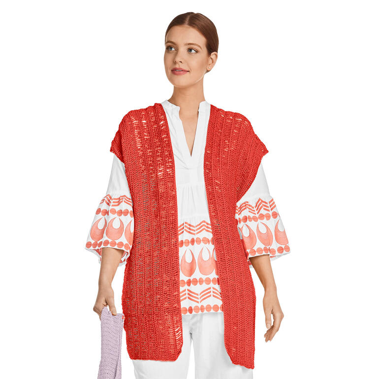 Frau mit roter gehäkelter Weste über einem weißen Oberteil.