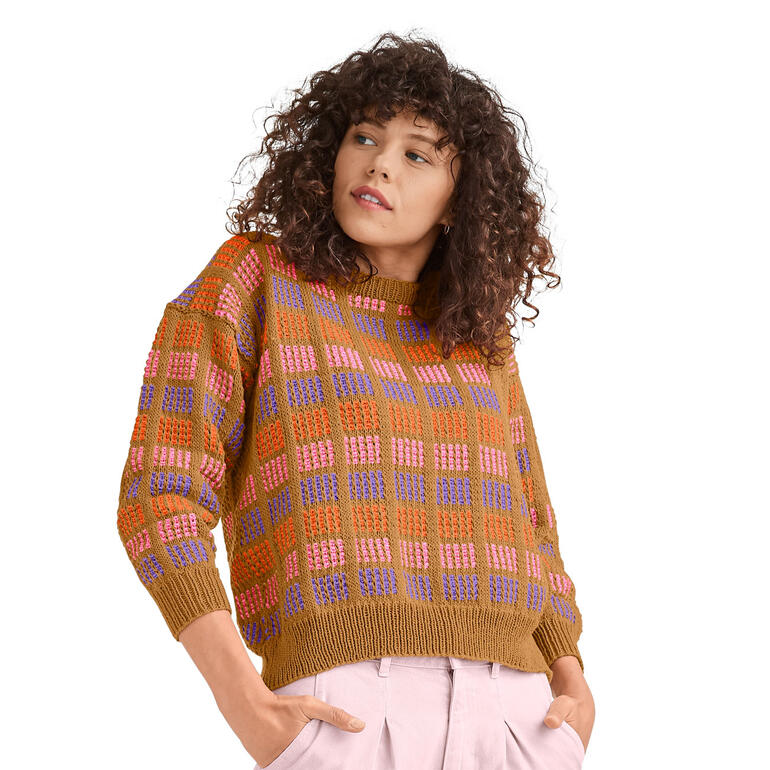 Dame in gemustertem Pullover aus Cotonia II mit lockigen Haaren.