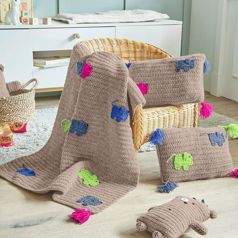 Decke und zwei Kissen aus Poco mit bunten Tiermotiven.