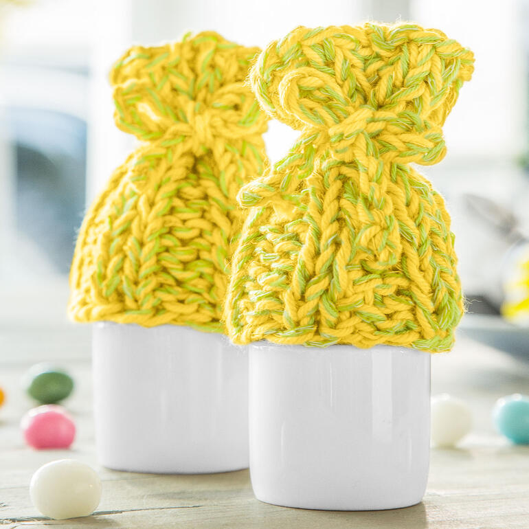 Gelber Eierwärmer aus Cotonara, hält Eier warm, mit einer Schleife.