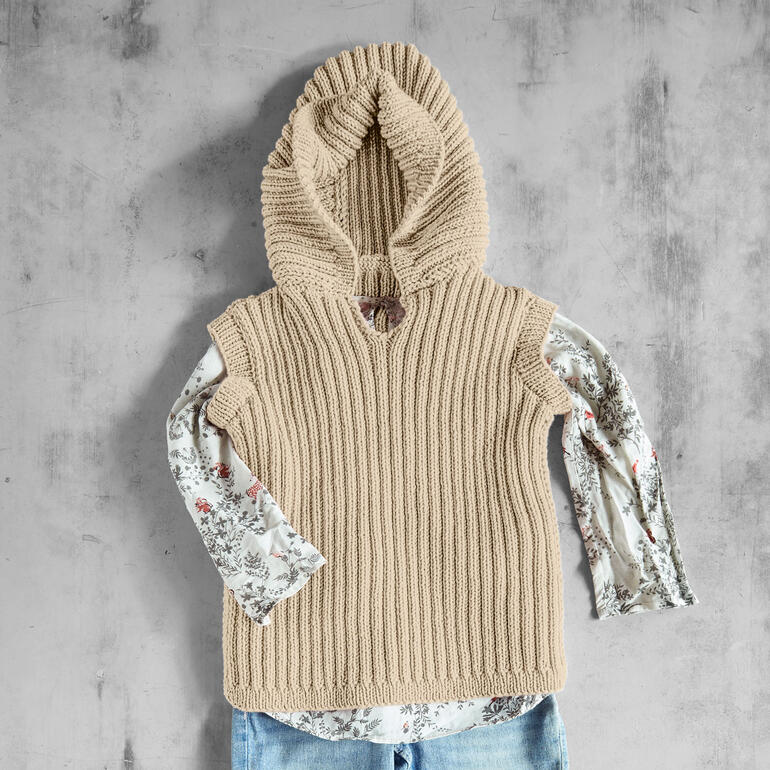 Beige Kapuzenpullover über einem gemusterten Shirt.