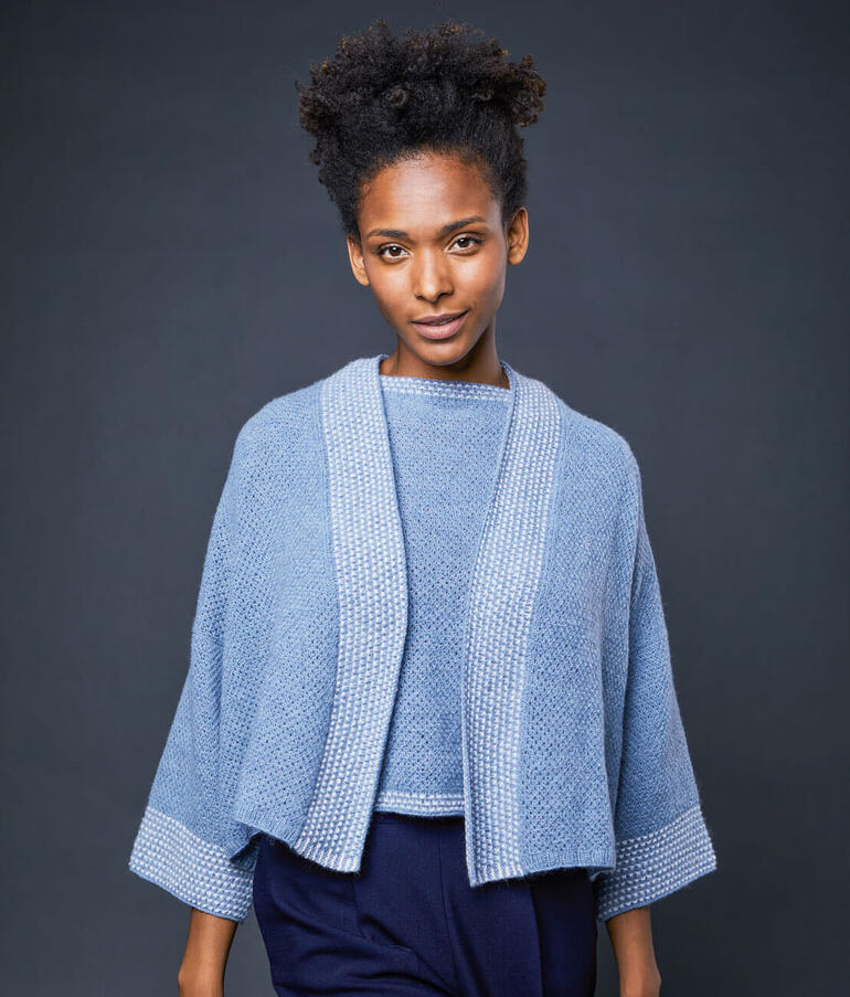 Frau in einer blauen Kimonojacke mit weit geschnittenen Ärmeln.