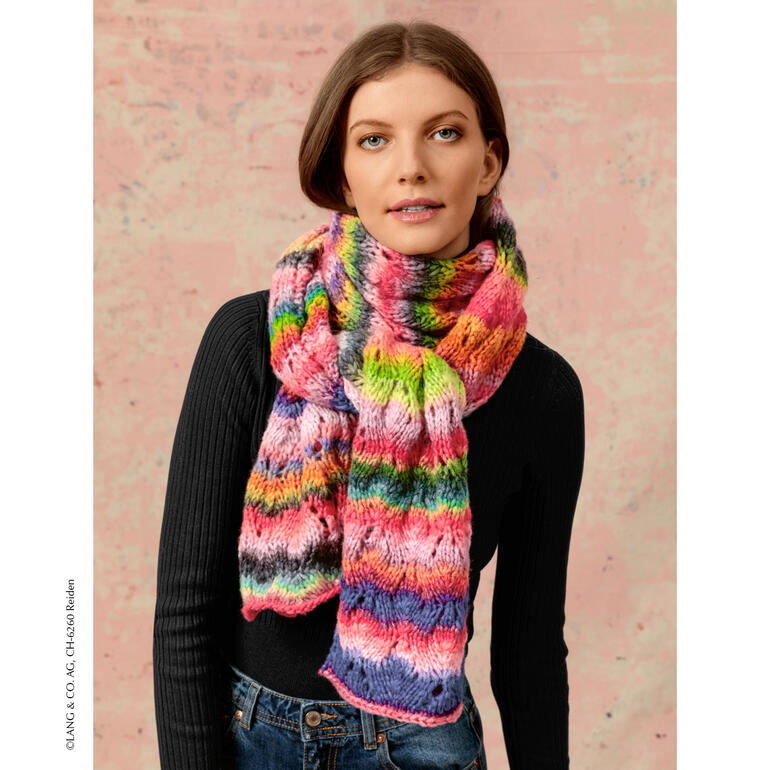 Frau trägt bunten Schal aus Cloud von LANG Yarns, lächelnd vor pastellfarbenem Hintergrund.
