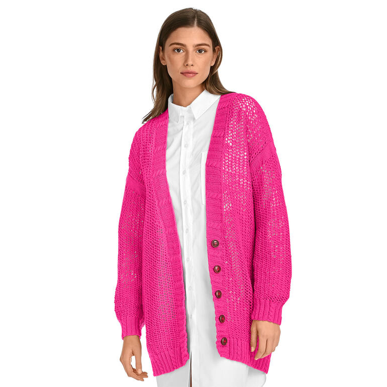 Frau in einer leuchtend rosa Jacke aus Merino-Cotton, mit Knöpfen und lächelnd.