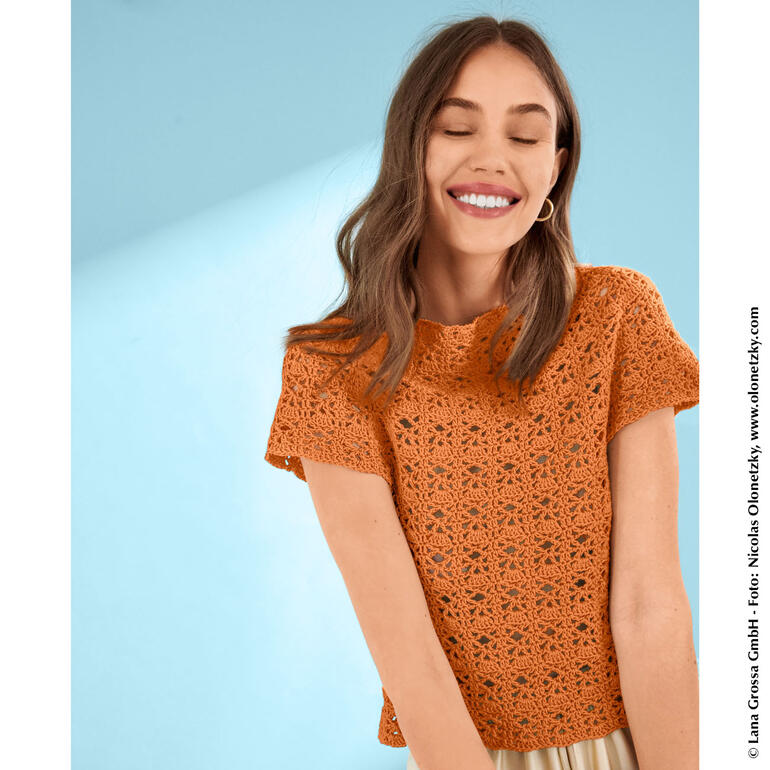 Häkeltop aus Landlust® Sommerseide in orange, lächelnd getragen von einer Frau.