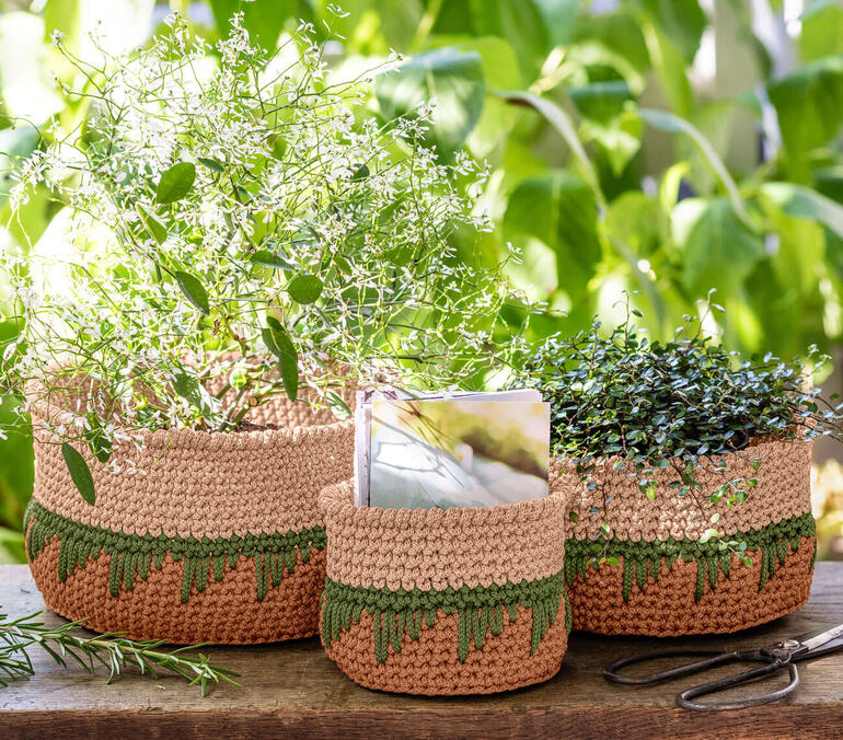 Drei dekorative Körbe aus Rope, bepflanzt mit Pflanzen, im Hintergarten.