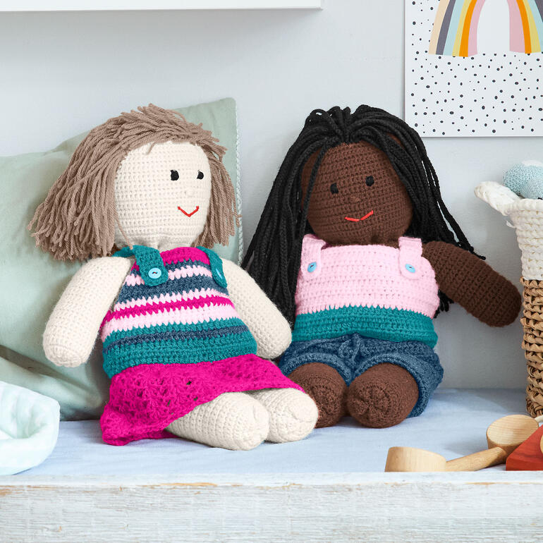 Zwei gehäkelte Puppen aus Poco, eine in gestreiftem Kleid und die andere in rosa Oberteil.