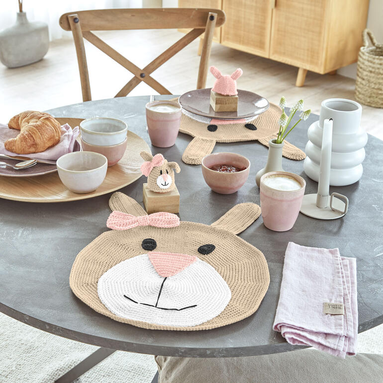 Tischdekoration mit einem braunen Hasen-Motiv und Geschirr auf einem Tisch.