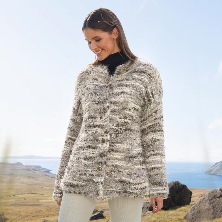 Frau in gestrickter Jacke aus Bo. und Nuovo Merino 120 im Freien, vor einer Landschaft.