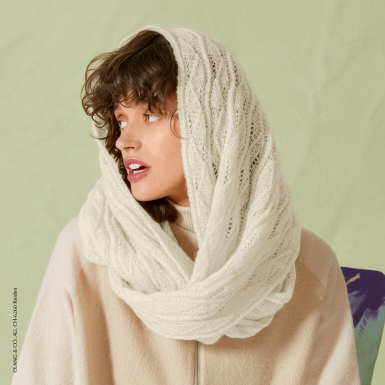 Frau in weißem Doppelloop, trägt eine lockere Jacke.