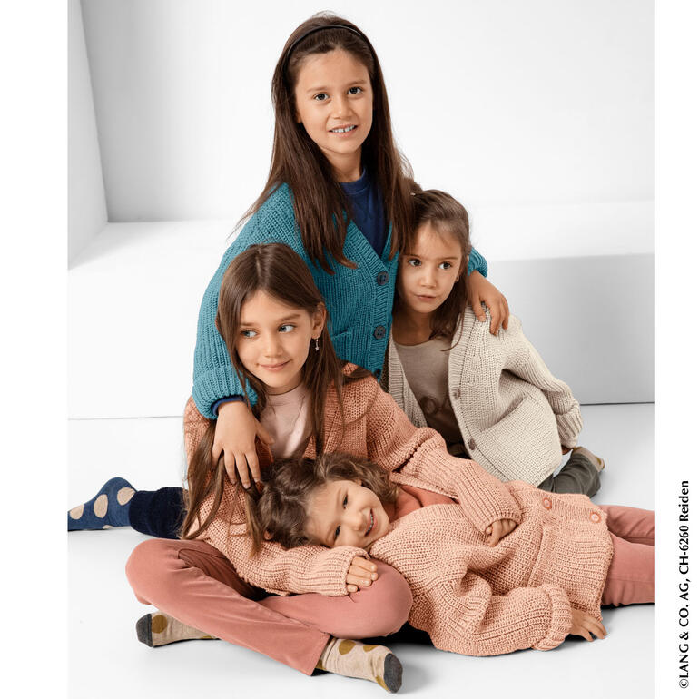 Vier Mädchen in verschiedenen Jacken, sitzen zusammen auf dem Boden.