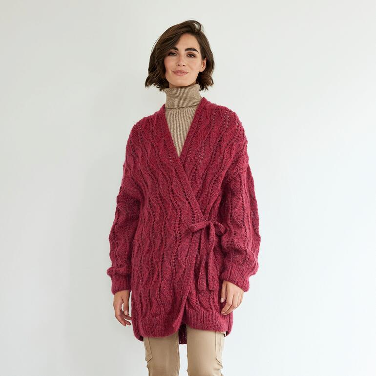 Frau in roter langer Jacke aus Frigga, lächelt in die Kamera.