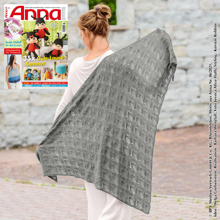 Dreiecktuch aus Rima in Grau, getragen von einer Frau, die es über die Schultern drapiert.