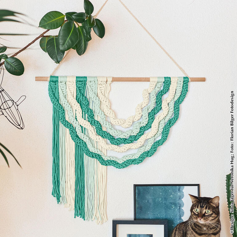 Hängende Wanddeko aus Makramee in Grün und Creme mit einer Katze.