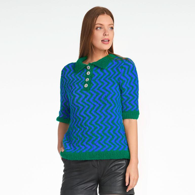 Frau in buntem Polo-Pullover mit Knöpfen vor sanftem Hintergrund.