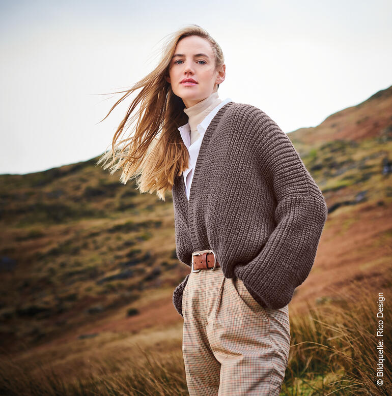 Frau in braunem, grob gestricktem Cardigan über einem weißen Hemd