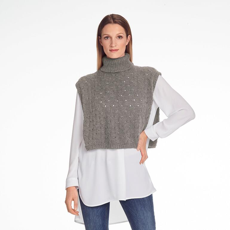 Kurzer Überwurf aus Enny-Wolle in grauer Farbe, modeliert von einer Frau.