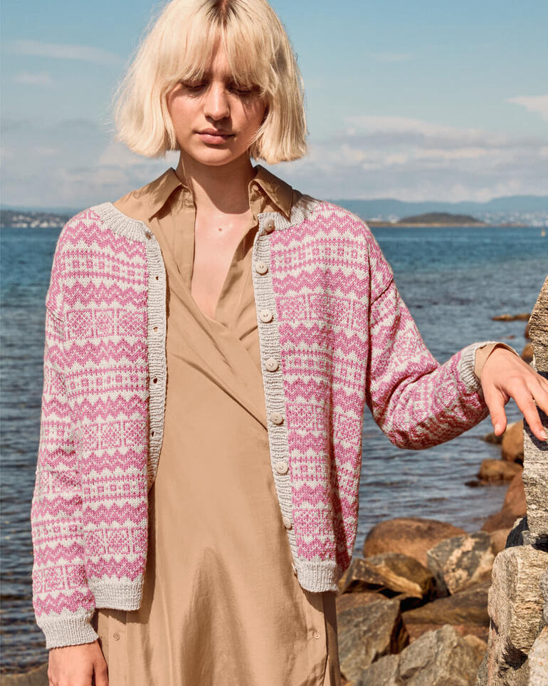 Jacke aus Sisu in hellem Rosa und Grau, Figur einer Frau in freier Natur.