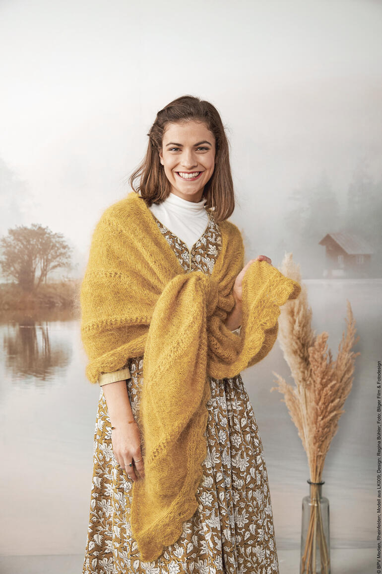 Tuch aus Kid Mohair in warmem Gelb, um die Schultern einer Frau geschlungen.