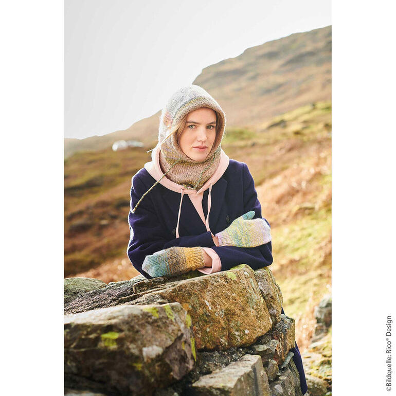 Frau trägt Balaclava und Fäustlinge im Freien, umgeben von Bergen.