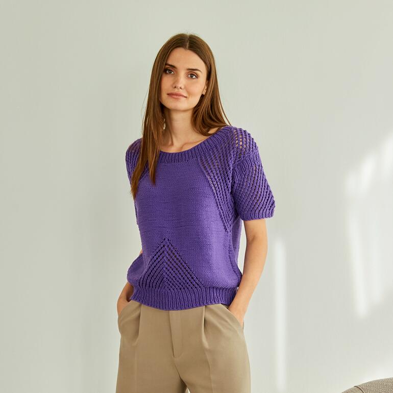Frau trägt einen lila Pullover aus Cotonara, mit strukturiertem Muster und weiten Ärmeln.