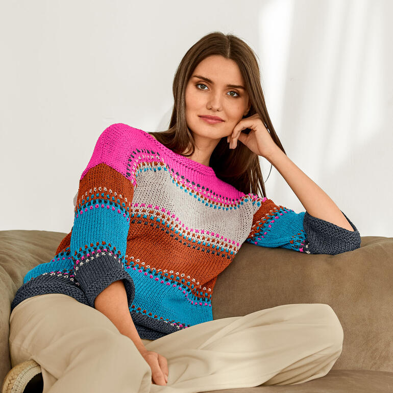 Frau in einem bunten Pullover aus Bandana, lässig auf einer Couch sitzend.