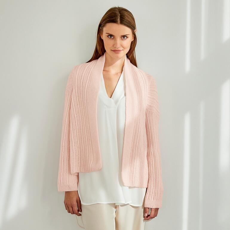 Frau in einer rosa Jacke aus Rima, elegant mit Bluse kombiniert.