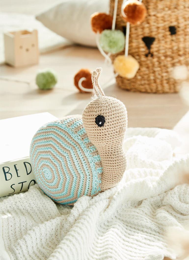 Große gehäkelte Schnecke aus Cotonia II auf einem weißen Tuch.