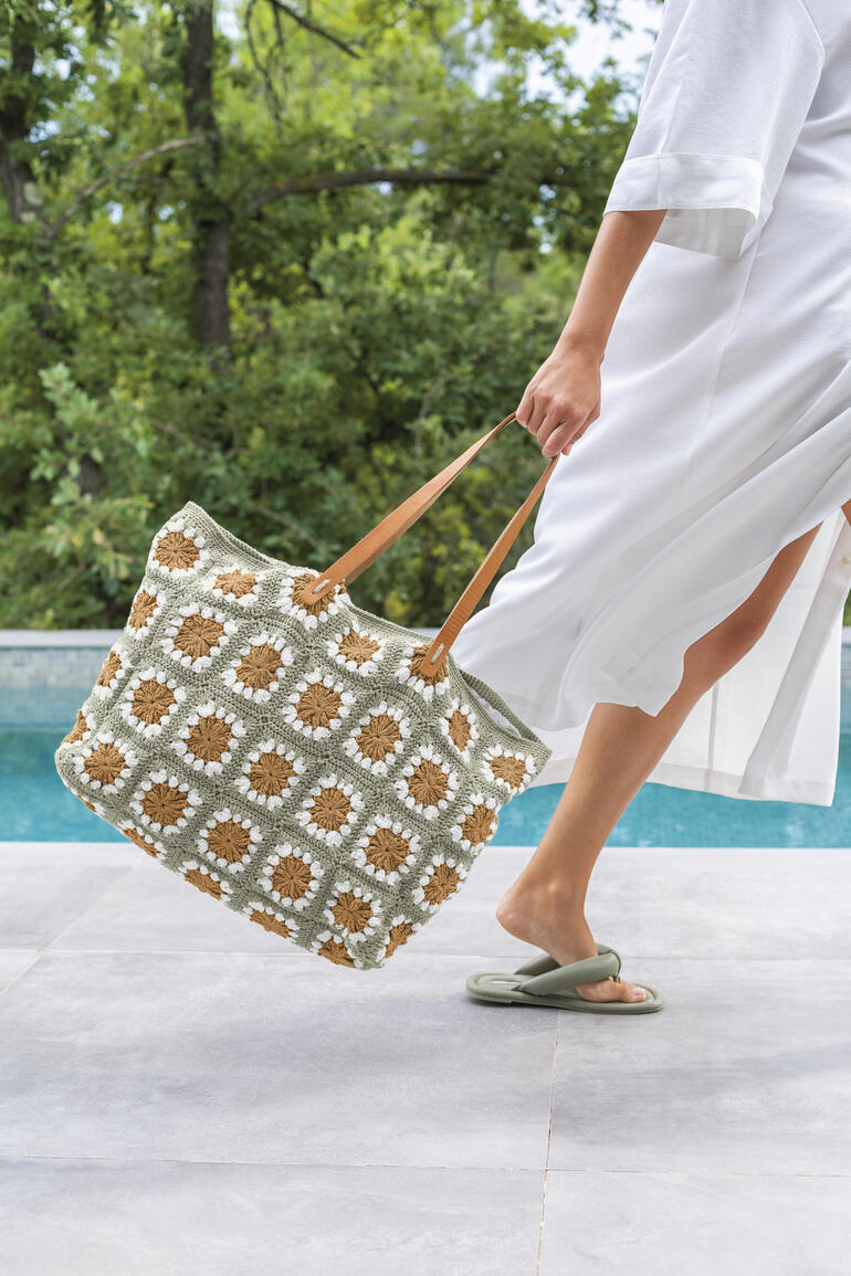 Häkeltasche aus SeaCell Cotton in grün mit braunen Grannymuster, getragen von einer Frau.