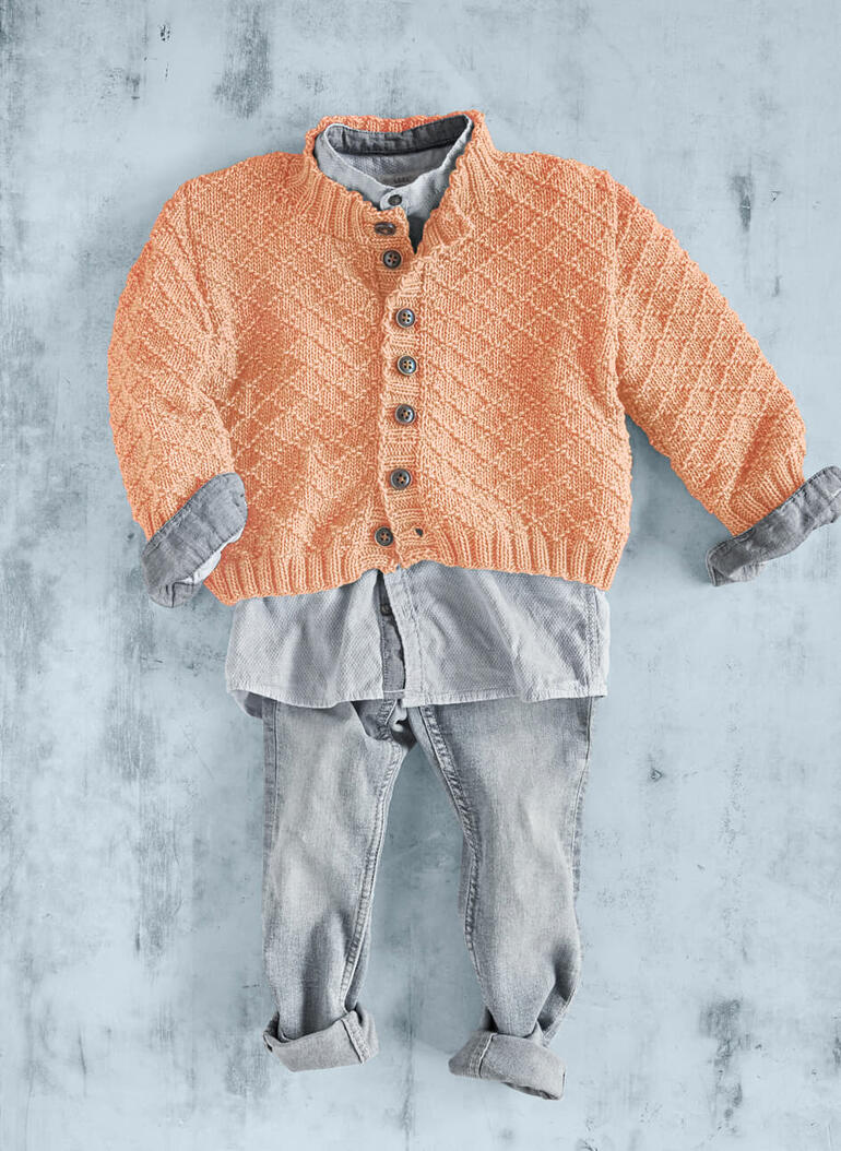 Orangefarbene Strickjacke mit Knöpfen, über einem blauen Hemd und Jeans drapiert.