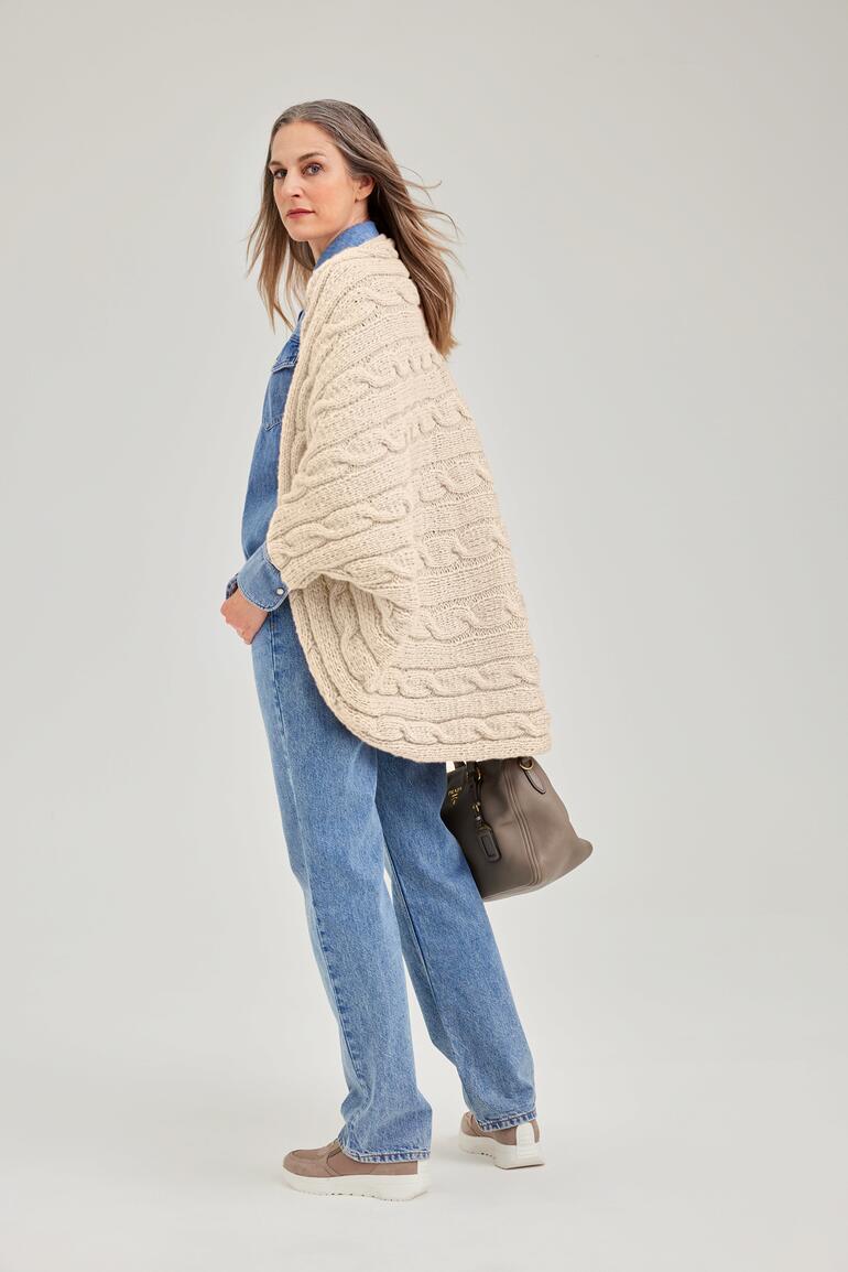 Ärmelschal aus NewWool, getragen von einer Frau in lässiger Kleidung, die weggeht.