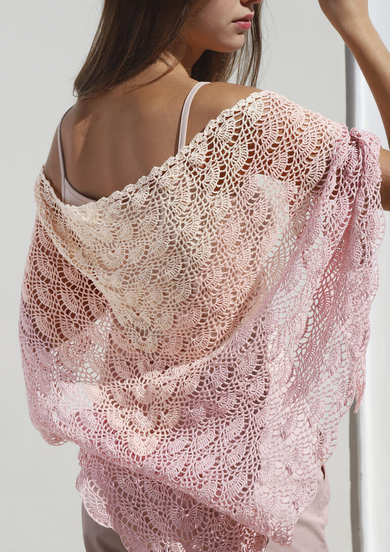 Dreieckstuch aus Freccia in sanften Rosa- und Pfirsichtönen, getragen von einer Frau.