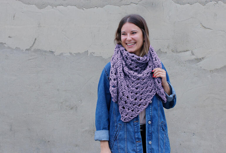Dreieckstuch aus No. 1 von myboshi in lila, getragen von einer Frau mit Jeansjacke.