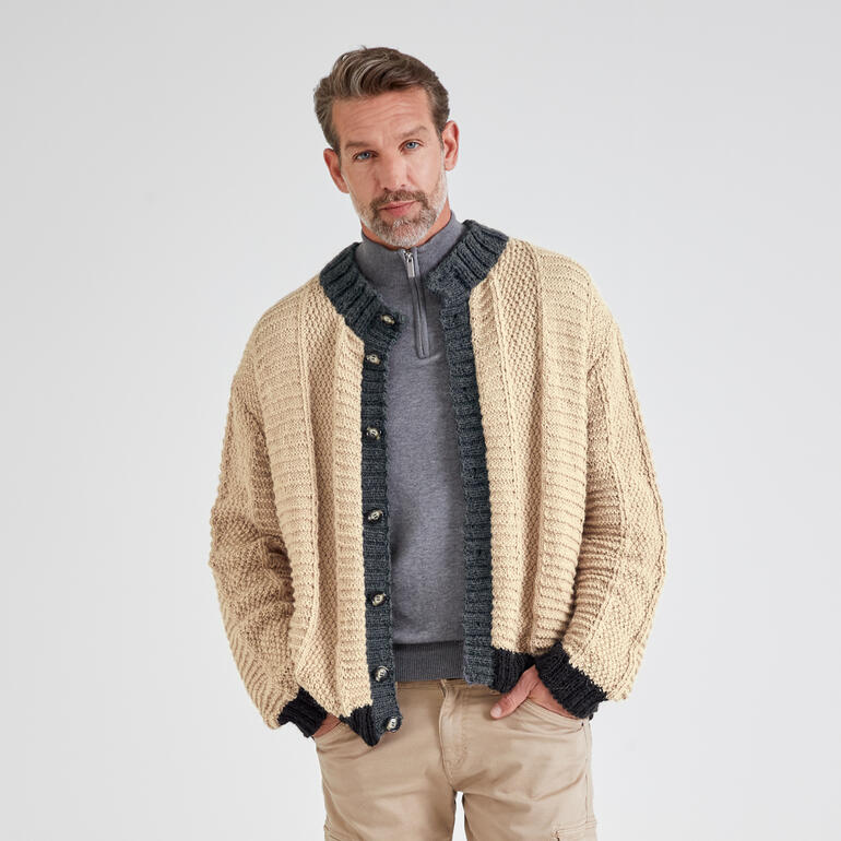 Mann in beiger Herrenjacke steht mit verschränkten Armen vor neutralem Hintergrund.