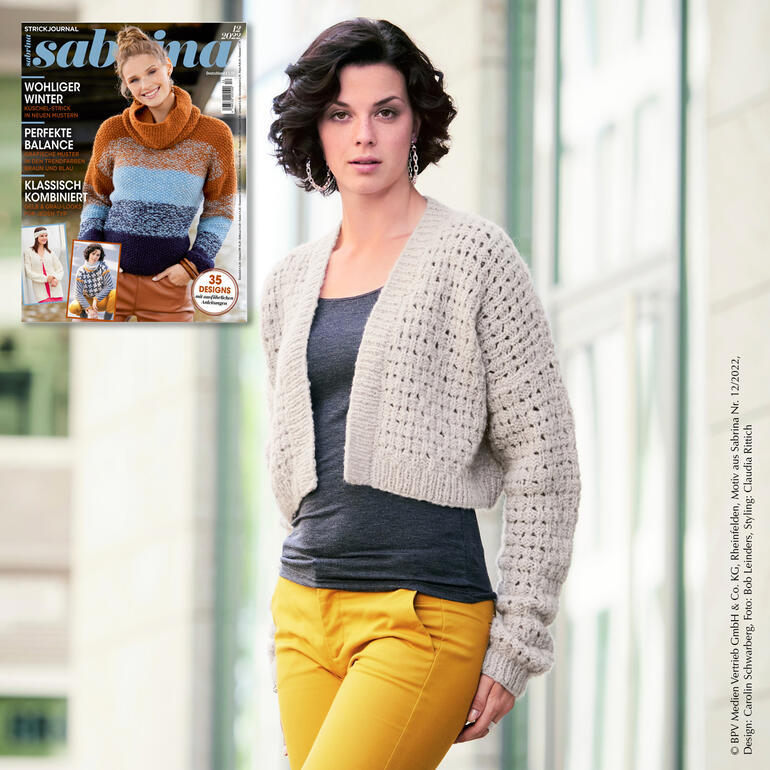 Frau in kurzem, beigefarbenem Jacke mit dicker Wolle vor heller Wand.