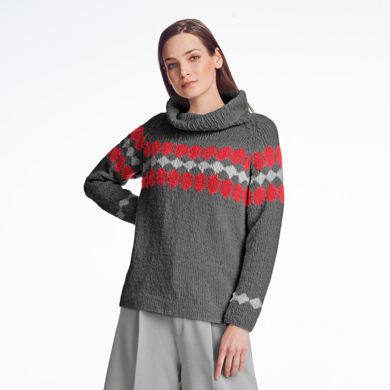 Frau in grauem Pullover mit auffälligem Muster schaut zur Seite.