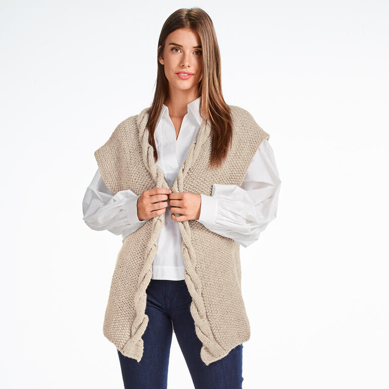 Frau trägt eine beige Weste aus Monello-90 Uni, lächelt in die Kamera.