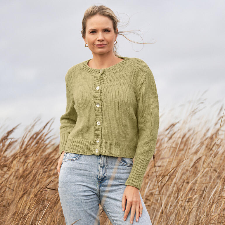 Frau trägt eine grüne Jacke aus Four Seasons in einer windigen Landschaft.